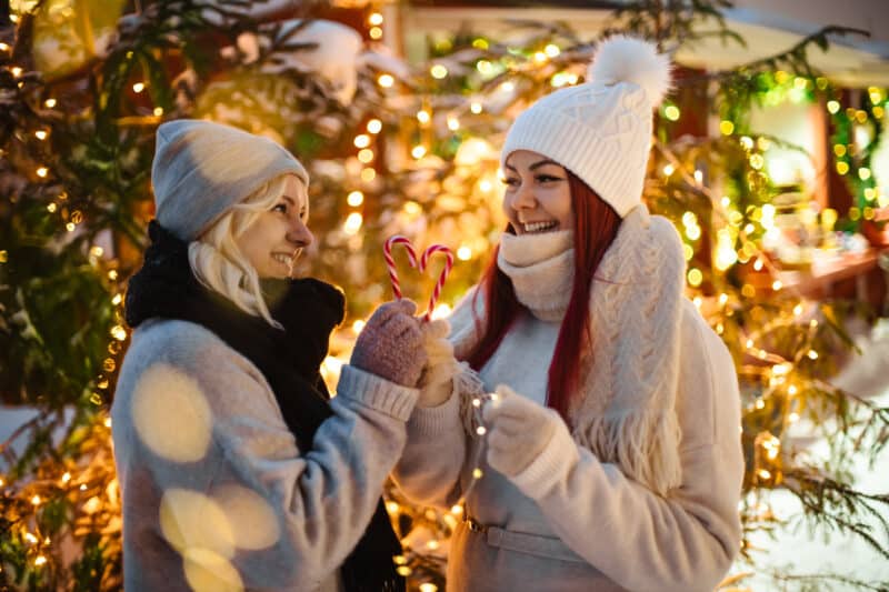 Kaksi naista ulkona, pitävät karamellikeppejä.