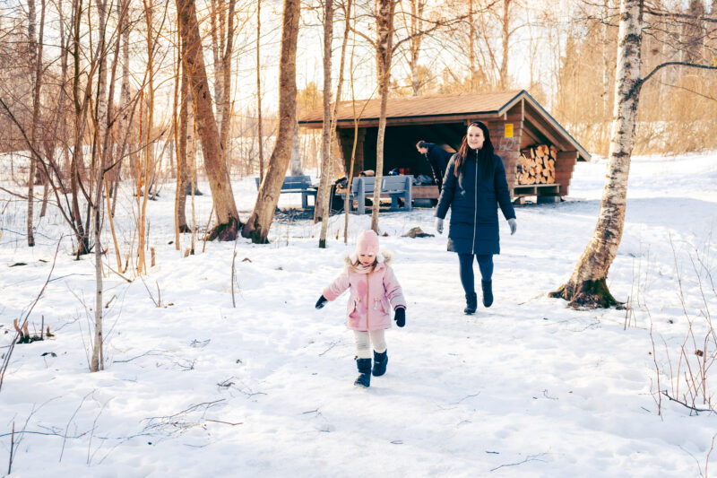 Lapsi ja äiti astelevat polkua pitkin Kirkkojärven laavulla talvipäivänä