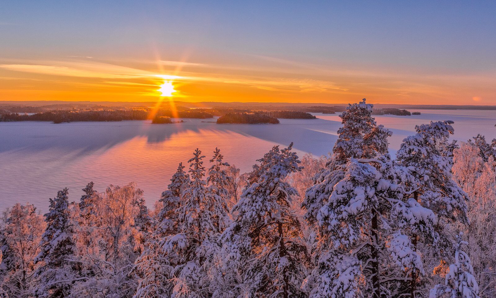 Maisema harjulta kuvattuna talvella auringon laskiessa