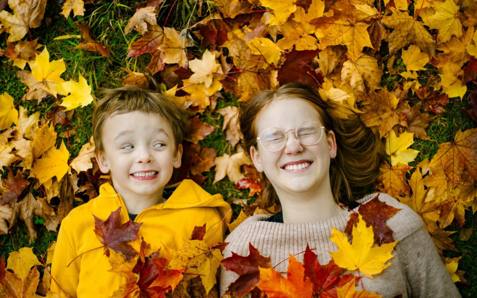 Kaksi lasta syksyisten lehtien peitossa