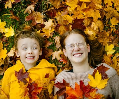 Kaksi lasta syksyisten lehtien peitossa