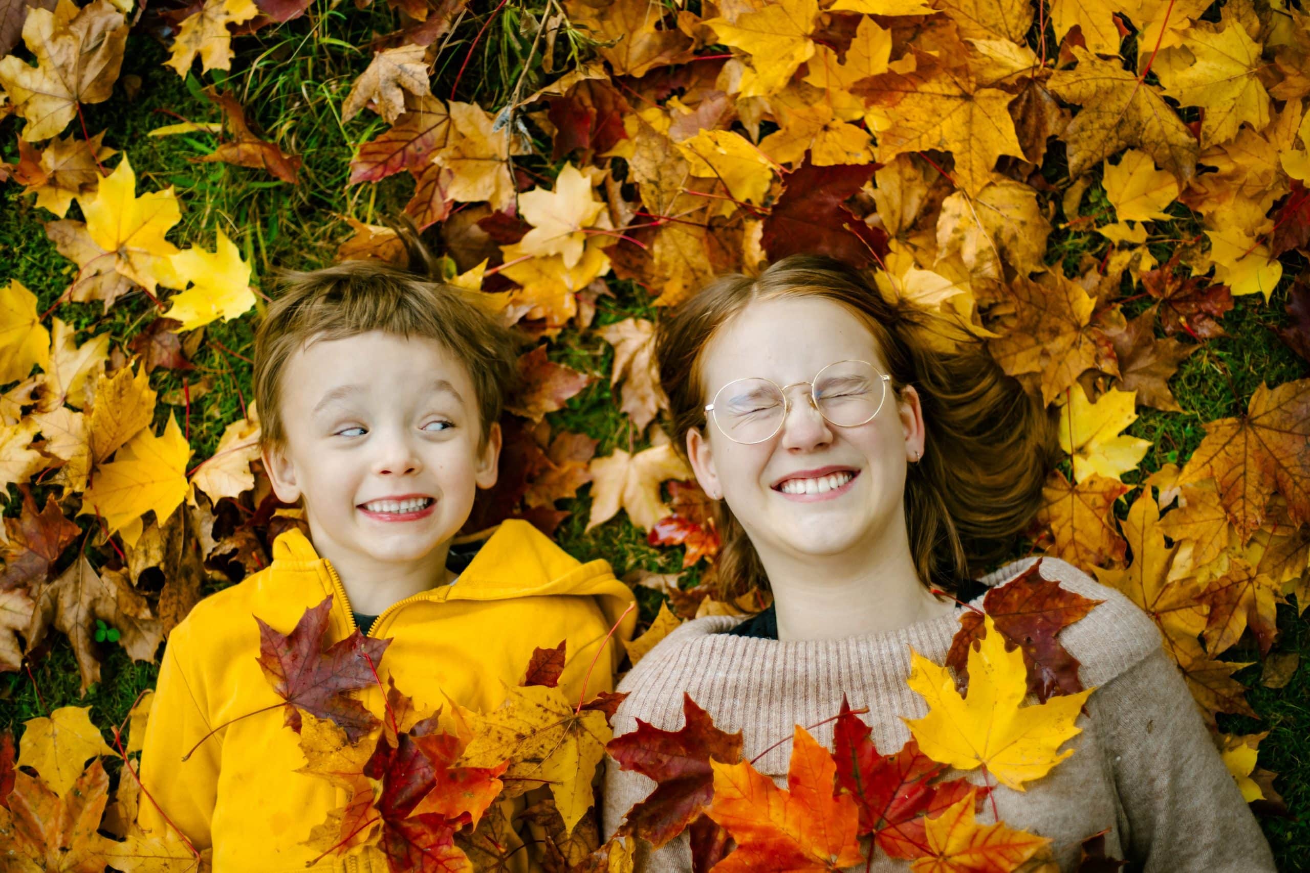 Kaksi lasta syksyisten lehtien peitossa